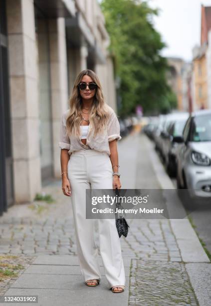 Janina Pfau wearing white crop top, beige shirt and pants, Dior saddle bag and Dior slides on June 15, 2021 in Berlin, Germany.