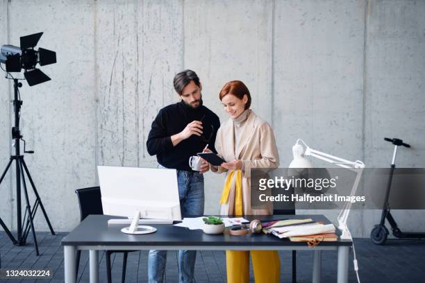 man and woman entrepreneurs designers with tablet and computer, brainstorming. - clothing design studio stock pictures, royalty-free photos & images