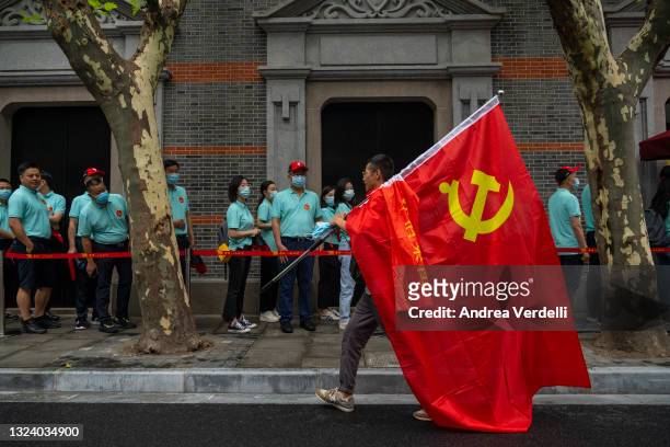 Man carries the hammer and sickle flag and other visitors queue up outside of the Memorial of the First National Congress of the Communist Party of...
