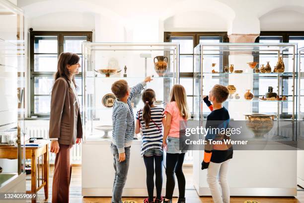 group of children looking at museum display with teacher - purity imagens e fotografias de stock