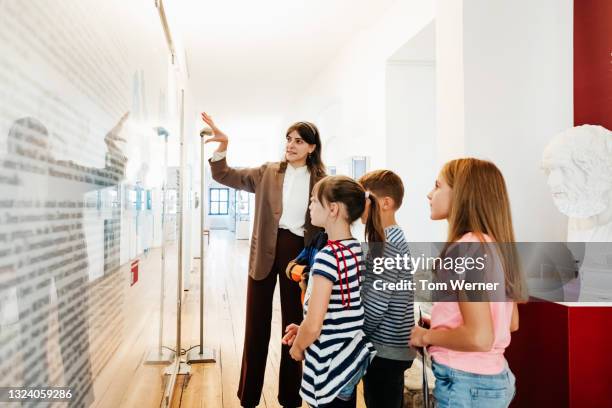 teacher showing pupils exhibit while on museum field trip - guide touristique photos et images de collection