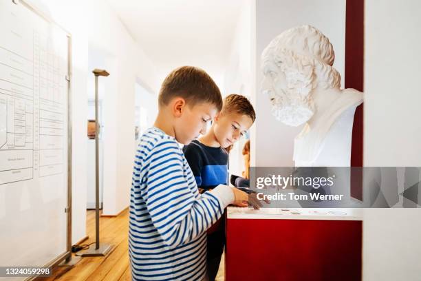 two boys reading the label on marble bust at museum - bust museum imagens e fotografias de stock