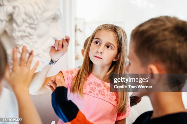 young girl touching marble bust in museum - bust museum stock-fotos und bilder