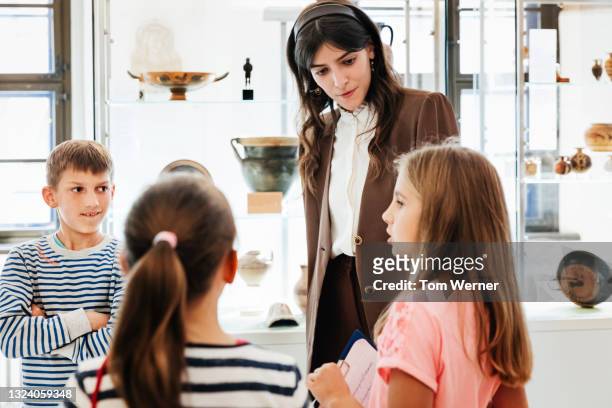 teacher listening to young pupils while on museum field trip - memory and human rights museum stock pictures, royalty-free photos & images