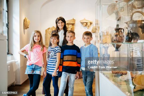 group portrait of teacher with young pupils during museum field trip - portrait of school children and female teacher in field stock pictures, royalty-free photos & images