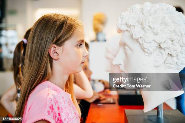 young girl looking closely at classical bust in museum - 胸像 ストックフォトと画像