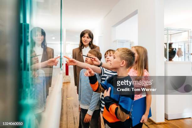 kids looking at objects on display in museum - teacher stock-fotos und bilder