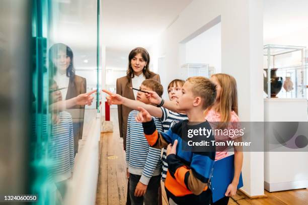 kids looking at objects on display in museum - profesor fotografías e imágenes de stock