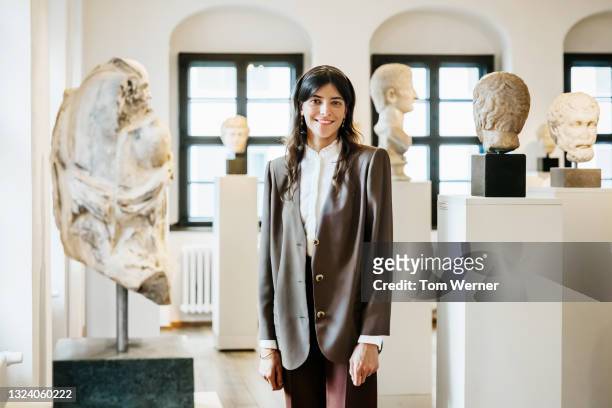 portrait of school teacher standing amidst classical sculptures in museum - guide 個照片及圖片檔