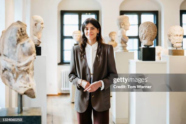 portrait of school teacher standing among classical sculptures in museum - museum guide stock-fotos und bilder