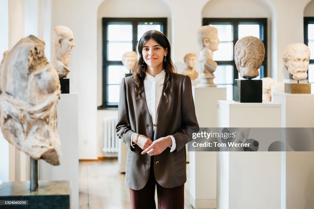 Portrait Of School Teacher Standing Among Classical Sculptures In Museum