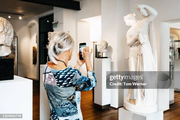 mature woman taking photo of classical sculpture - bust museum imagens e fotografias de stock