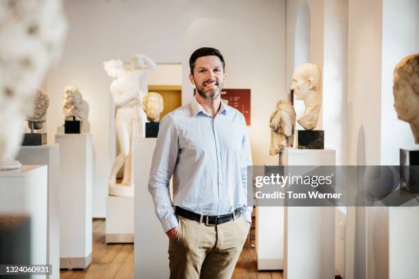 man standing in museum exhibit smiling - museum tour stock pictures, royalty-free photos & images