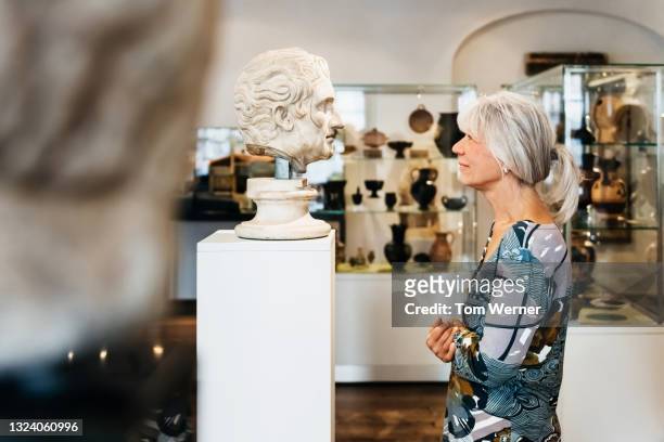 Mature Woman Viewing Classical Busts In Historical Museum
