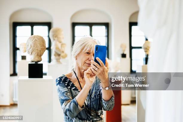 mature woman taking photos of museum exhibits - bust museum imagens e fotografias de stock