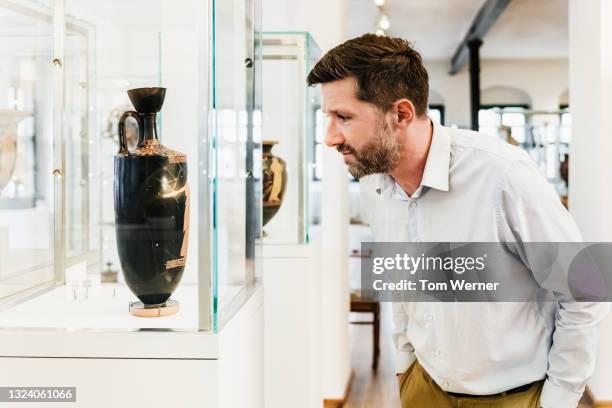 man examining ancient vase on display in museum - ancient vase stock pictures, royalty-free photos & images