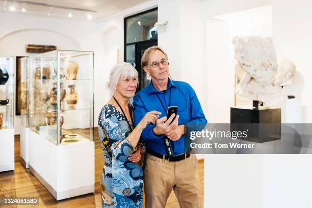mature couple reading information while looking at museum exhibit - museum visit stock pictures, royalty-free photos & images
