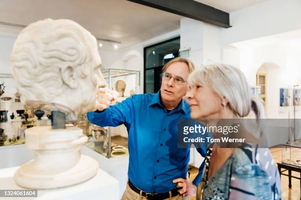 mature couple discussing classical bust on display in museum - bust museum imagens e fotografias de stock