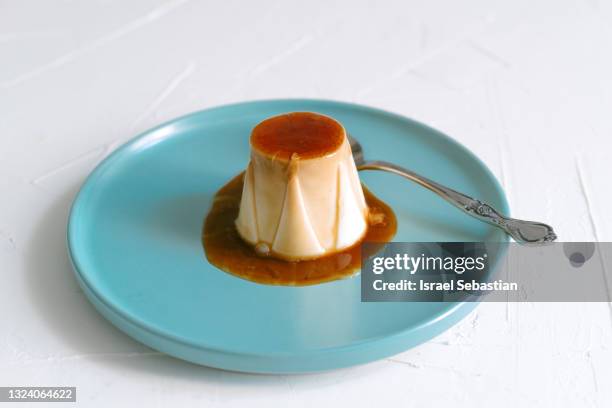 close-up view of cheese pudding with delicious caramel on top on a blue plate. - pudim-de-leite imagens e fotografias de stock