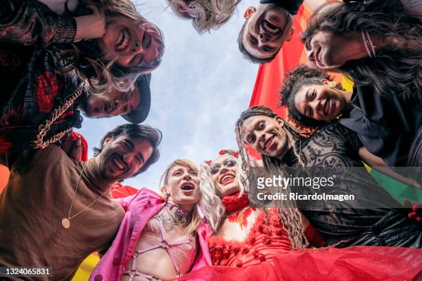 group of friends of different sexual orientations celebrate gay pride by wearing their rainbow flag and their multicolored outfits - beautiful transvestite 個照片及圖片檔