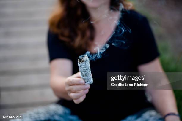 woman holds white sage bundle in hand - close up - lantana camara stock pictures, royalty-free photos & images