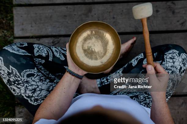 woman sits cross-legged and holds a singing bowl in her hands - top view - gong stock pictures, royalty-free photos & images