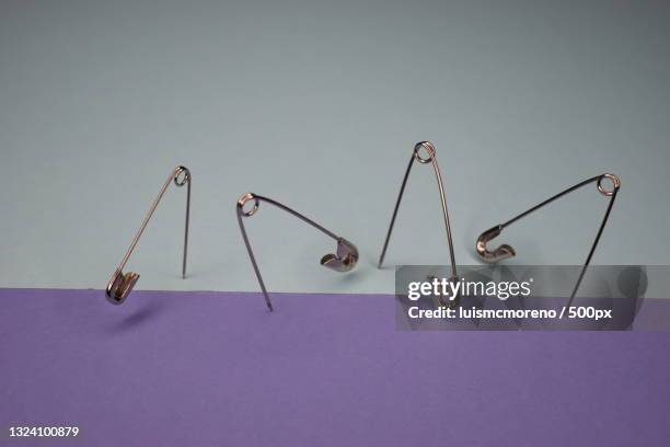 close-up of safety pins on purple background - imperdible fotografías e imágenes de stock