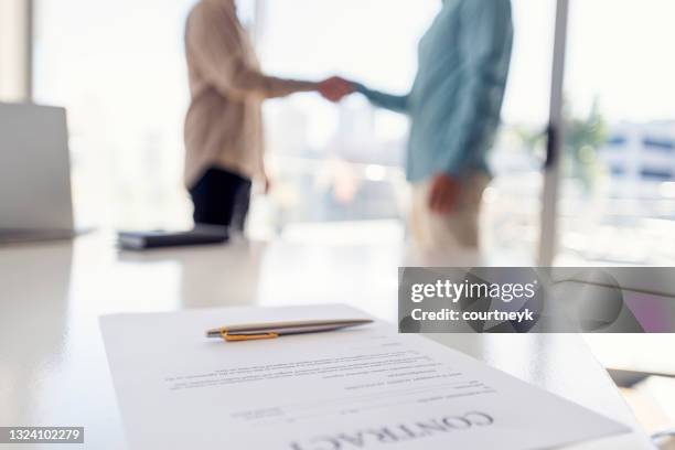 dois empresários apertando as mãos com um contrato. - legal agreement - fotografias e filmes do acervo