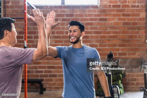 two men high five after exercising at gym - hi five gym stockfoto's en -beelden