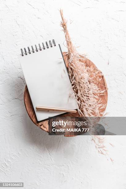 top view, flat lay blank template of a spiral notebook and gold pencil on teak wood bowl with bundle golden wild oat (avena fatua). concept of greeting card for mothers day, wedding, happy event or birthday. - avena fatua stock pictures, royalty-free photos & images