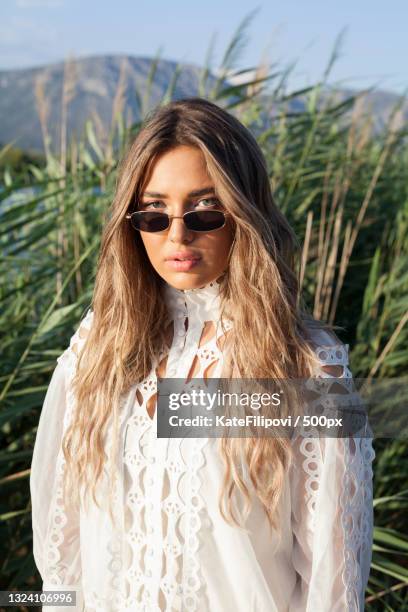 portrait of young woman in sunglasses standing on field,komin,croatia - kate young styliste photos et images de collection