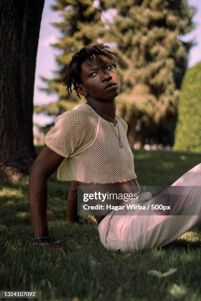 portrait of young man sitting on field,kelowna,british columbia,canada - fashion editorial stock pictures, royalty-free photos & images