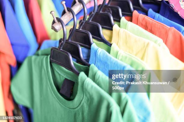 close-up of colorful t-shirts hanging on rack - camisa de colores fotografías e imágenes de stock