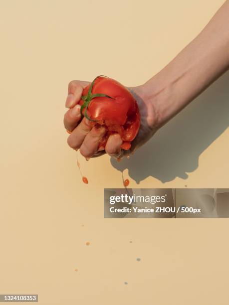 cropped hand of person crushing tomato against wall,food waste concept - crushed photos et images de collection