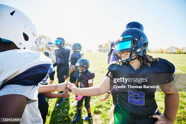 medium shot of smiling young football player shaking hands with opponent after game on fall afternoon - safety american football player 個照片及圖片檔