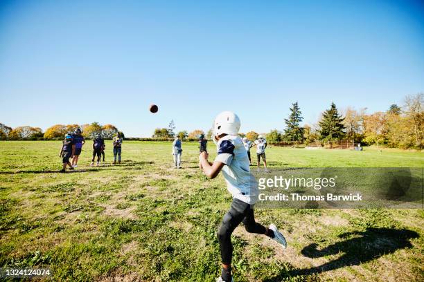 wide shot of young football player going out for pass during practice on fall afternoon - american football uniform stock pictures, royalty-free photos & images
