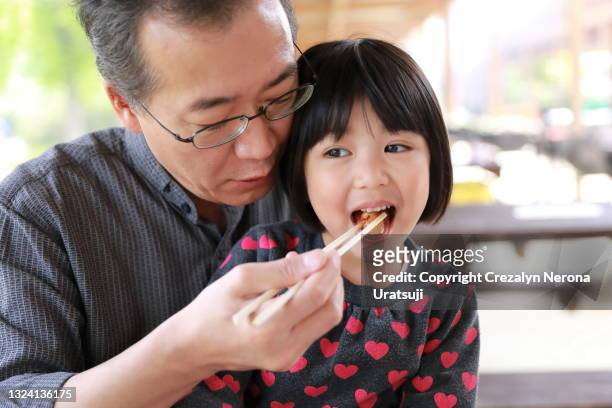 father feed her child with bbq meal father and child quality time - filipino family eating fotografías e imágenes de stock