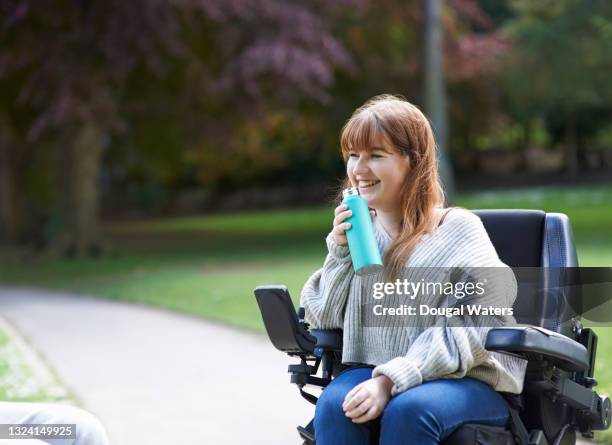 disabled woman with plastic free reusable water bottle in park. - frau rollstuhl selbstständigkeit stock-fotos und bilder