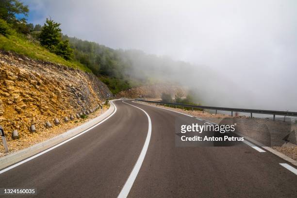 mountain road in clouds in kotor, montenegro. the road to mount lovcen - winding road mountain stock pictures, royalty-free photos & images