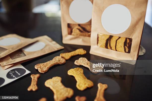 schuss von frisch gebackenen hundekeksen und verpackten bestellungen auf einer küchentheke während des tages - haustierfutter stock-fotos und bilder