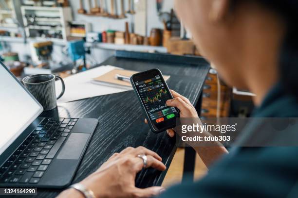 uomo adulto medio che utilizza uno smartphone per monitorare la sua criptovaluta e il trading di azioni - borsa foto e immagini stock