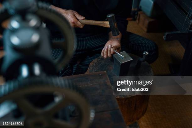 platero adulto medio martilleando plata en preparación para hacer joyas - vanguardista fotografías e imágenes de stock