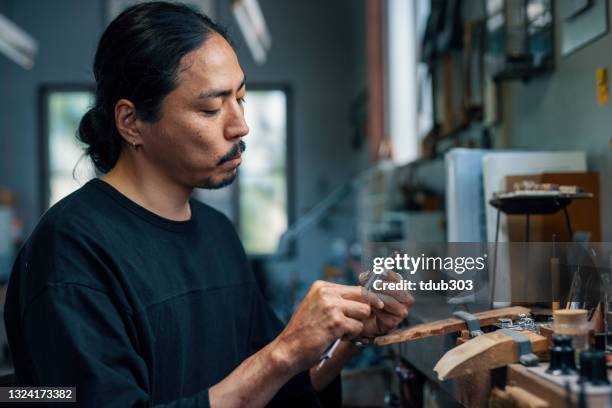 mid adult silversmith inspecting a piece of silver jewellery - traditional craftsman stock pictures, royalty-free photos & images