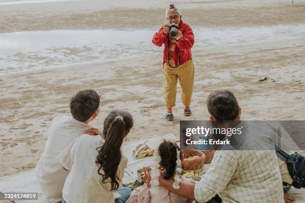 part time job of senior woman photographing unity family during eco-friendly picnic time on vacation - stock photo - family photo shoot stock pictures, royalty-free photos & images