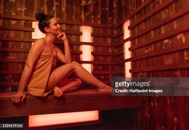 happy mid adult woman in sauna, relaxing. - infrared lamp 個照片及圖片檔