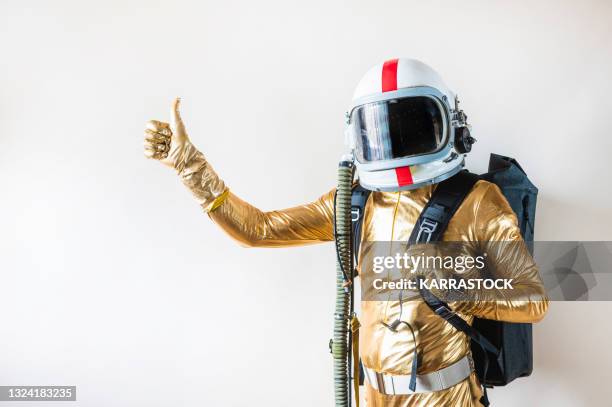 man dressed as an astronaut with backpack making gestures - gold suit stock-fotos und bilder