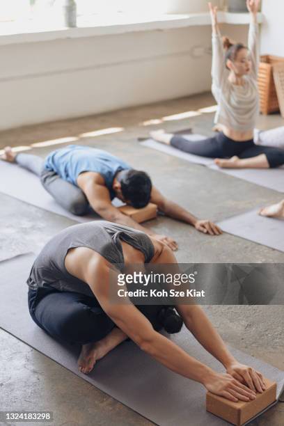 Hombre chino asiático estirando y respirando durante una clase de yoga