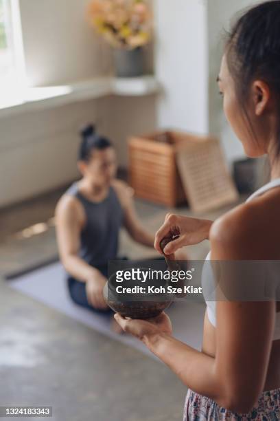 Female Asian yoga teacher conducting a meditation session with a singing bowl