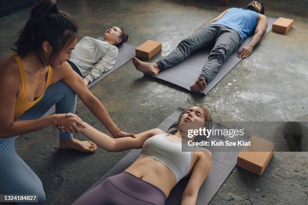 asian female yoga teacher massages for her students - yoga instructor stock pictures, royalty-free photos & images