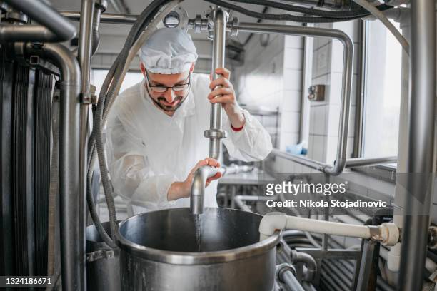 hombre que trabaja en una fábrica de productos lácteos - fabrica alimentos fotografías e imágenes de stock